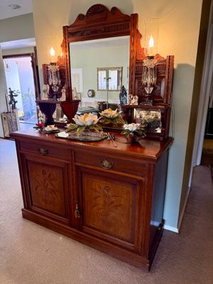 Antique carved wood sideboard with a large attached mirror, side shelves, and decorative floral door panels.