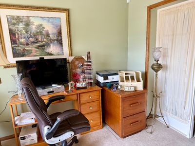 Home office workspace featuring a wooden desk, executive swivel chair, computer monitor, HP printer, small filing cabinet, ornate brass...