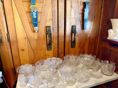 Large collection of cut glass and pressed crystal tableware displayed on a folding table, including footed bowls, compotes, and small...