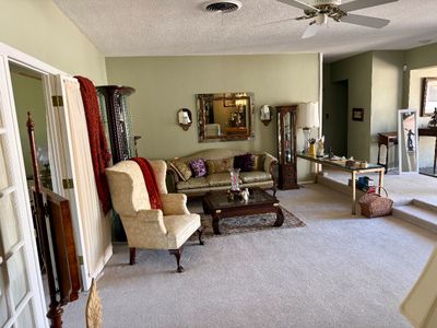 Living room setup featuring a damask wingback armchair, a patterned three-cushion sofa, glass display cabinets, and various accent...