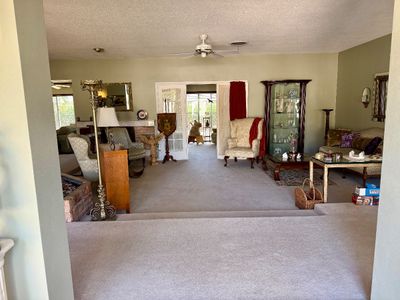 Spacious living area featuring traditional furniture, including a pair of wingback armchairs, a wooden glass-front curio cabinet, a sofa,...