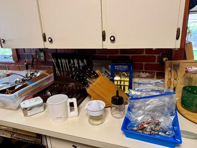 Assortment of kitchenware including a cutlery knife block, flatware set in a wooden chest, small appliances, and silverplate utensils on...