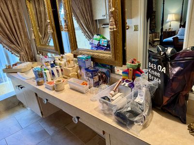 Assortment of bathroom accessories, personal care items, medical supplies, and a Tech 843 OA knee brace, displayed on a vanity.