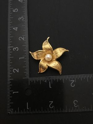 Sale Photo Thumbnail #40: Vintage Sarah Coventry gold-tone textured flower brooch featuring a faux pearl center. Marked 'SARAH COVENTRY' on the back. Measures approximately 2 inches wide. Features a safety clasp on the pin back. In good vintage condition with minimal wear.