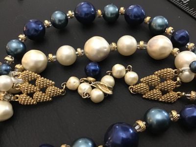 Sale Photo Thumbnail #43: Vintage mid-century style multi-strand statement necklace featuring tiered strands of faux pearls and lustrous blue faux pearls separated by gold-tone spacers. Includes decorative textured gold-tone hardware end connectors and an adjustable hook closure w
