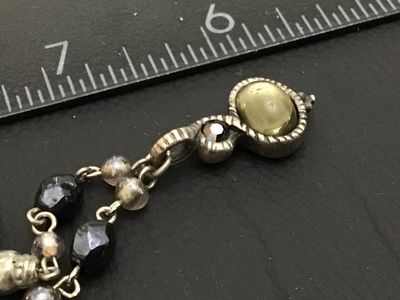 Sale Photo Thumbnail #148: A beaded costume jewelry necklace featuring faceted black and smoky beads, silver-tone metal links, and a drop pendant with a yellowish faux pearl cabochon and a small dark rhinestone accent. Includes a lobster claw clasp, an extender chain, and a circula