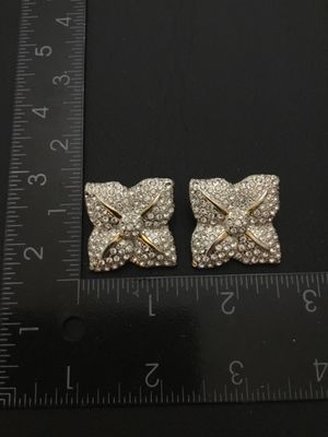 Sale Photo Thumbnail #130: Pair of bold vintage clip-on statement earrings featuring pave-set clear rhinestones in a four-petal or four-point star shape with gold-tone accents. Clip-on backs are functional. Each earring measures approximately 1.25 inches across. Good pre-owned vint