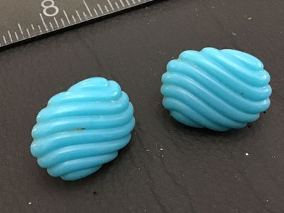 Sale Photo Thumbnail #114: Pair of vintage light blue molded glass or plastic clip-on earrings featuring a ribbed/swirl texture design with gold-tone clip backs. Each earring measures approximately 1 inch in length. Overall good vintage condition with minor surface wear consistent 