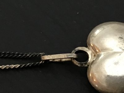 Sale Photo Thumbnail #131: A fine silver necklace featuring a puffed heart pendant. The pendant bail is stamped '925' for sterling silver, while the chain clasp tag is stamped '835' alongside a maker's mark/hallmark. Features a curb chain with a spring ring clasp. Shows light tarni