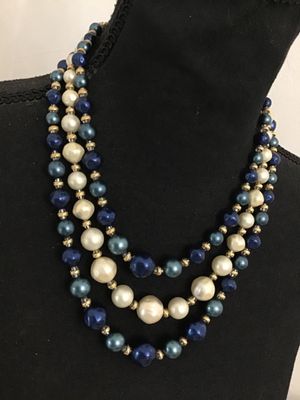 Sale Photo Thumbnail #46: Vintage mid-century style multi-strand statement necklace featuring tiered strands of faux pearls and lustrous blue faux pearls separated by gold-tone spacers. Includes decorative textured gold-tone hardware end connectors and an adjustable hook closure w