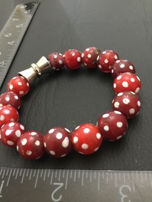 Sale Photo Thumbnail #239: A stretch bead bracelet featuring red Venetian glass 'skunk' beads with white polka dot spots, accented by a silver-tone metal bead. The bracelet measures approximately 2.5 inches in inner diameter. Shows minor age-appropriate wear and slight imperfection
