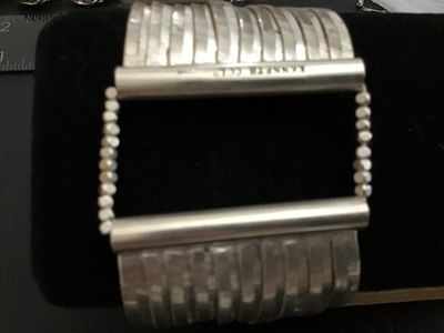 Sale Photo Thumbnail #137: A Kenneth Cole wide cuff bracelet featuring multiple flexible silver-tone herringbone chains gathered into polished metallic end bars with beaded accents. Marked Kenneth Cole on the clasp bar. Shows light wear consistent with pre-owned condition.