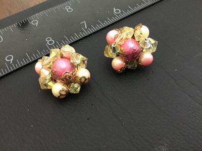 Sale Photo Thumbnail #97: Pair of vintage cluster-style clip-on earrings featuring yellow iridescent Aurora Borealis crystal beads, pink center beads, and faux pearls in gold-tone metal settings. Each earring measures approximately 1 inch in diameter. Clips show light metal oxidat