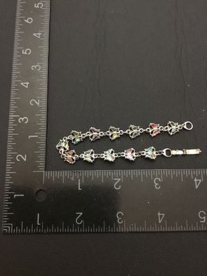 Sale Photo Thumbnail #208: A silver-tone link bracelet featuring connected butterfly links inlaid with colorful crushed shell / abalone inlay. Measures approximately 7 inches long end-to-end with a fold-over clasp. Good condition with minimal signs of wear.