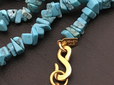 Sale Photo Thumbnail #202: Signed Kenneth Jay Lane necklace featuring turquoise-colored stone chips with gold-tone metal findings and S-hook clasp. Measures approximately 32 inches in total length. Good vintage condition with no visible damage.