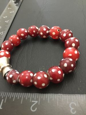 Sale Photo Thumbnail #242: A stretch bead bracelet featuring red Venetian glass 'skunk' beads with white polka dot spots, accented by a silver-tone metal bead. The bracelet measures approximately 2.5 inches in inner diameter. Shows minor age-appropriate wear and slight imperfection