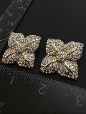 Sale Photo Thumbnail #134: Pair of bold vintage clip-on statement earrings featuring pave-set clear rhinestones in a four-petal or four-point star shape with gold-tone accents. Clip-on backs are functional. Each earring measures approximately 1.25 inches across. Good pre-owned vint