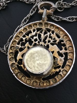 Sale Photo Thumbnail #29: Vintage West 17 pendant watch featuring a decorative ornate filigree medallion housing encircled with faux pearls. The watch face features Roman numerals. Includes a long   Not tested silver-tone chain. Marked 'West 17' on the watch dial. Metal shows ligh