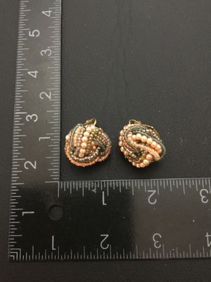 Sale Photo Thumbnail #155: Pair of vintage clip-on cluster earrings featuring woven seed beads and faux pearls in shades of peach, grey, and metallic tones on gold-tone backing plates. Each earring measures approximately 1 inch in diameter. In good vintage condition with secure cli