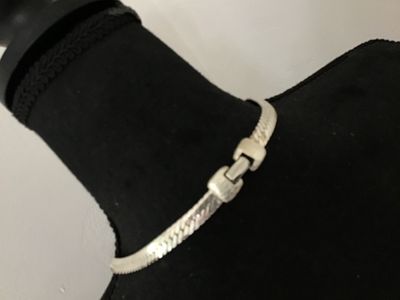 Sale Photo Thumbnail #104: A vintage silver-tone flat herringbone chain necklace by Napier. Features a secure fold-over clasp marked 'Napier PAT. 4,774,743' and 'NAPIER©'. The piece shows a classic flat-link woven design with a shiny finish. In good vintage condition with minor su