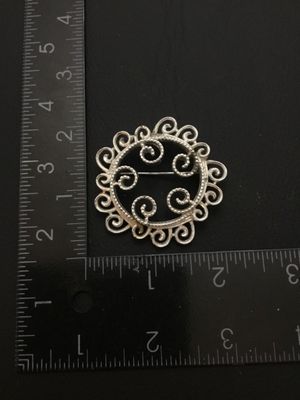 Sale Photo Thumbnail #21: Vintage Sarah Coventry silver-tone brooch featuring an intricate openwork scrollwork design. Marked © SARAH COV on the back. Measures approximately 1.75 inches in diameter. Features a functional rollover safety clasp. Good vintage condition with light we