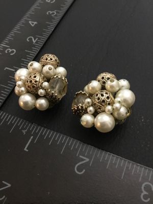 Sale Photo Thumbnail #229: Pair of vintage cluster clip-on earrings featuring faux pearls, faceted glass beads, and gold-tone pierced filigree beads set on filigree backing plates. Each earring measures approximately 1 inch in diameter. Clip backs function properly. Shows mild age-