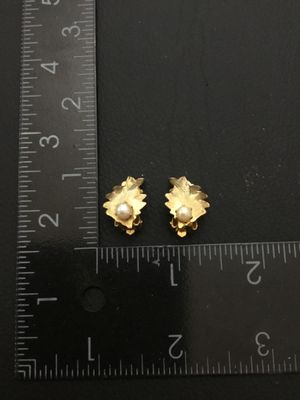Sale Photo Thumbnail #181: Pair of vintage gold-tone textured leaf clip-on earrings, each accented with a faux pearl center. Each earring measures approximately 3/4 inch long by 1/2 inch wide. Clip backs are in good working order. Good pre-owned condition with minor vintage wear.
