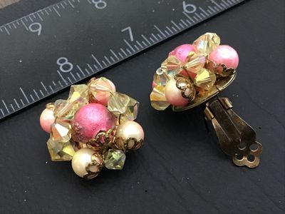 Sale Photo Thumbnail #94: Pair of vintage cluster-style clip-on earrings featuring yellow iridescent Aurora Borealis crystal beads, pink center beads, and faux pearls in gold-tone metal settings. Each earring measures approximately 1 inch in diameter. Clips show light metal oxidat