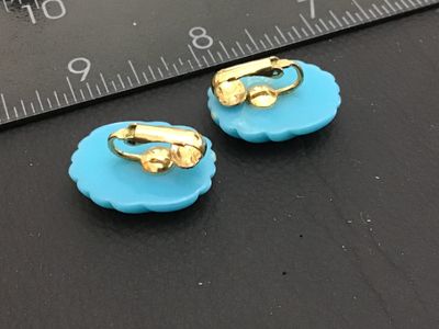 Sale Photo Thumbnail #117: Pair of vintage light blue molded glass or plastic clip-on earrings featuring a ribbed/swirl texture design with gold-tone clip backs. Each earring measures approximately 1 inch in length. Overall good vintage condition with minor surface wear consistent 