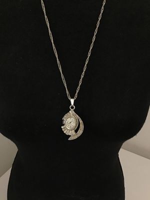 Sale Photo Thumbnail #30: Vintage Belforte pendant watch styled as a necklace. Features an ornate silver-tone, fan-shaped housing set with marcasite-style accents, an oval watch face with silvertone hands and numbers, and a matching chain. The back of the watch casing is marked 'B