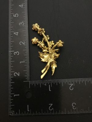 Sale Photo Thumbnail #60: A vintage gold-tone floral bouquet brooch signed RMN, featuring textured leaves and flowers set with sparkling pink rhinestones. Includes a rollover safety clasp on the back. Measures approximately 2.5 inches in length.