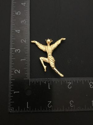 Sale Photo Thumbnail #69: A gold-tone costume jewelry brooch pin depicting a stylized dancing figure with outstretched arms. Features a textured finish and standard rollover pin clasp on the back. Measures approximately 2 inches tall by 2 inches wide. Good vintage condition with l