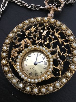 Sale Photo Thumbnail #26: Vintage West 17 pendant watch featuring a decorative ornate filigree medallion housing encircled with faux pearls. The watch face features Roman numerals. Includes a long   Not tested silver-tone chain. Marked 'West 17' on the watch dial. Metal shows ligh