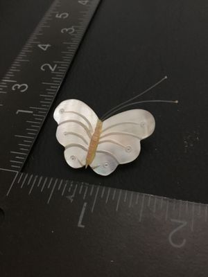 Sale Photo Thumbnail #110: Vintage carved mother of pearl butterfly brooch featuring carved shell wings, thin wire antennae, and a gold-tone pin bar back. Measures approximately 1.25 inches wide by 1 inch tall. In good pre-owned condition with functional clasp.