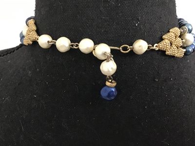 Sale Photo Thumbnail #48: Vintage mid-century style multi-strand statement necklace featuring tiered strands of faux pearls and lustrous blue faux pearls separated by gold-tone spacers. Includes decorative textured gold-tone hardware end connectors and an adjustable hook closure w