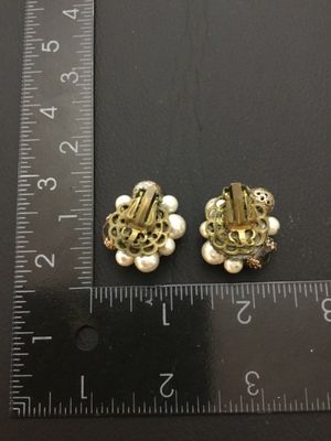 Sale Photo Thumbnail #225: Pair of vintage cluster clip-on earrings featuring faux pearls, faceted glass beads, and gold-tone pierced filigree beads set on filigree backing plates. Each earring measures approximately 1 inch in diameter. Clip backs function properly. Shows mild age-