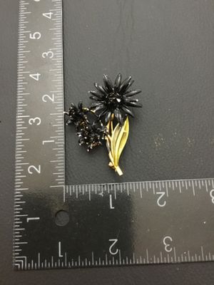 Sale Photo Thumbnail #214: Vintage mid-century style floral spray brooch featuring black enameled flower blossoms and textured gold-tone leaves. Measures approximately 2 inches long by 1.5 inches wide. Overall good vintage condition with pin back clasp in working order; minor ename