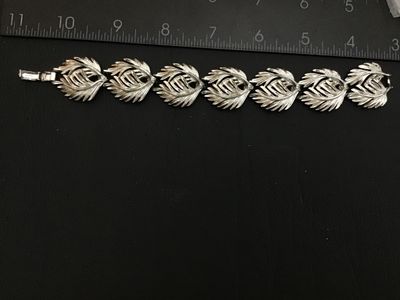 Sale Photo Thumbnail #189: A vintage Lisner silver-tone costume jewelry link bracelet featuring textured feather/leaf-shaped links and a fold-over clasp. Signed 'LISNER©' on the clasp. Measures approximately 7.5 inches in total length. Overall good vintage condition with light fin