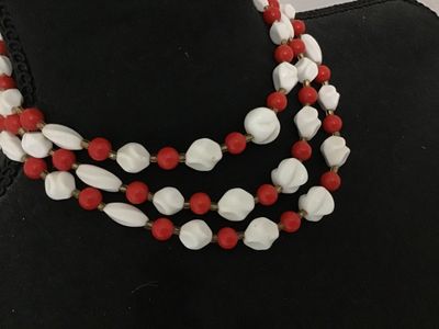 Sale Photo Thumbnail #172: A vintage 3-strand beaded necklace featuring red round beads and white molded/twisted geometric beads separated by small seed bead spacers. Includes an adjustable hook-and-tail clasp with gold-tone hardware. Shows light age-appropriate wear.