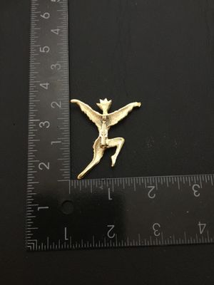 Sale Photo Thumbnail #73: A gold-tone costume jewelry brooch pin depicting a stylized dancing figure with outstretched arms. Features a textured finish and standard rollover pin clasp on the back. Measures approximately 2 inches tall by 2 inches wide. Good vintage condition with l