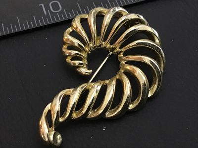 Sale Photo Thumbnail #182: A vintage gold-tone costume jewelry brooch featuring an openwork spiral shell or swirl design. Marked 'LISNER' on the back. Features a standard pin mechanism with rolling C-clasp. Shows light pre-owned wear consistent with age.