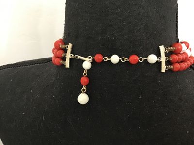 Sale Photo Thumbnail #175: A vintage 3-strand beaded necklace featuring red round beads and white molded/twisted geometric beads separated by small seed bead spacers. Includes an adjustable hook-and-tail clasp with gold-tone hardware. Shows light age-appropriate wear.