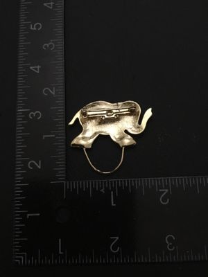 Sale Photo Thumbnail #166: Gold tone elephant brooch / pin clip featuring a textured finish and polished accents with a loop attachment at the bottom. Measures approximately 1.25 inches long by 1.5 inches tall including the loop. Good condition with standard pin bar closure on back