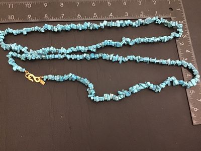 Sale Photo Thumbnail #204: Signed Kenneth Jay Lane necklace featuring turquoise-colored stone chips with gold-tone metal findings and S-hook clasp. Measures approximately 32 inches in total length. Good vintage condition with no visible damage.
