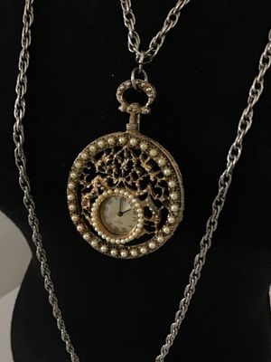 Sale Photo Thumbnail #20: Vintage West 17 pendant watch featuring a decorative ornate filigree medallion housing encircled with faux pearls. The watch face features Roman numerals. Includes a long   Not tested silver-tone chain. Marked 'West 17' on the watch dial. Metal shows ligh