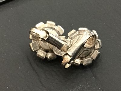 Sale Photo Thumbnail #238: Pair of vintage silver-tone clip-on earrings featuring a central faceted black rhinestone surrounded by a halo of clear rhinestones. Each earring measures approximately 0.5 inches in diameter. Show minor age-appropriate surface wear to metal backing.