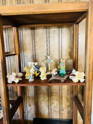 Collection of decorative figurines, decorative crosses, and small knick-knacks displayed on a wooden shelving unit.