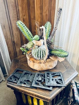 Decorative Southwestern cactus arrangement in a basket along with a four-piece set of cast iron Vermont Castings seasonal wall plaques.