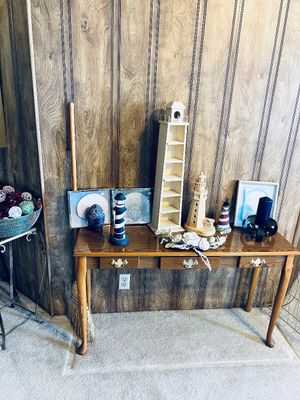 Traditional wooden sofa table featuring brass hardware, displayed alongside an assortment of nautical decor, including miniature...