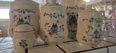 Sale Photo Thumbnail #5: Set of vintage ceramic kitchen canisters featuring a charming country folk art house and floral pattern.